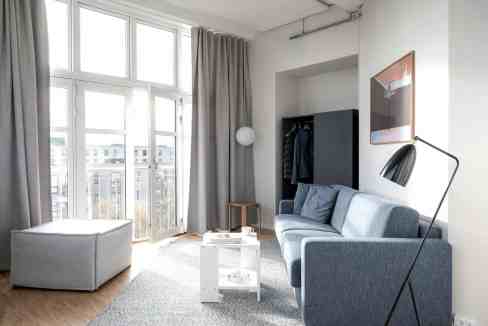 Bright living room with large windows, gray sofa, and minimalist decor.