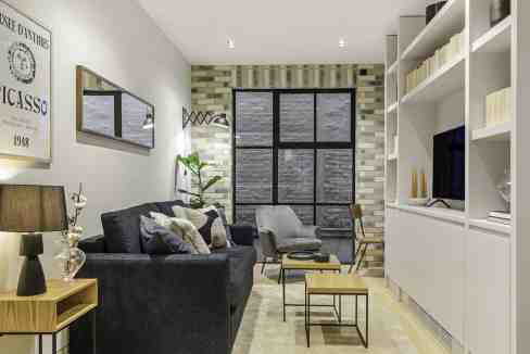 Contemporary living room with sofa, armchair, and large window in Chancery Lane Atelier.