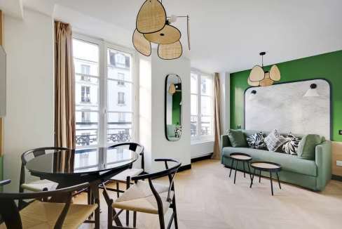 Bright living room with green wall, large windows, and contemporary furniture.