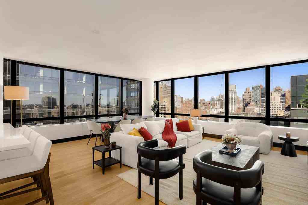 Bright city skyline view from a stylish modern living room with large windows.
