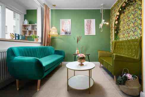 Cozy living room with vibrant green and teal furniture and decorative wall art.