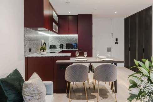 Contemporary kitchen and dining space featuring sleek cabinetry, modern appliances, and elegant seat.