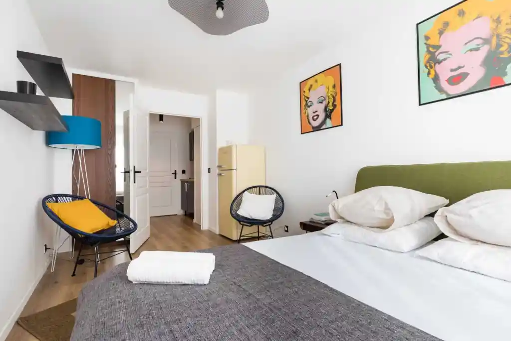 Bright bedroom with pop art portraits, cozy bed, and stylish decor.