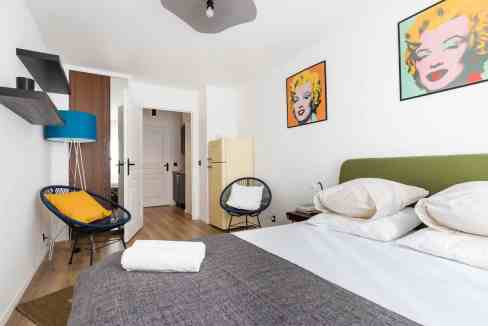 Bright bedroom with pop art portraits, cozy bed, and stylish decor.