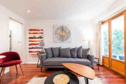 Bright living room featuring a gray sofa, colorful artwork, and wooden accents for a warm, inviting.