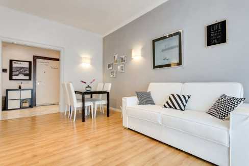 Bright living room with white sofa, wall art, and wooden flooring.