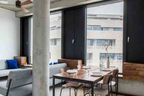 Urban living room with large windows, contemporary furniture, and natural light.