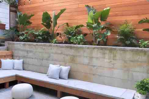 Cozy outdoor garden with wooden bench and lush greenery.
