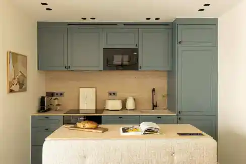 Blue kitchen cabinets with black hardware and beige countertop.