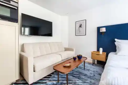 Modern living room with sofa, TV, and bedroom in South Pigalle.
