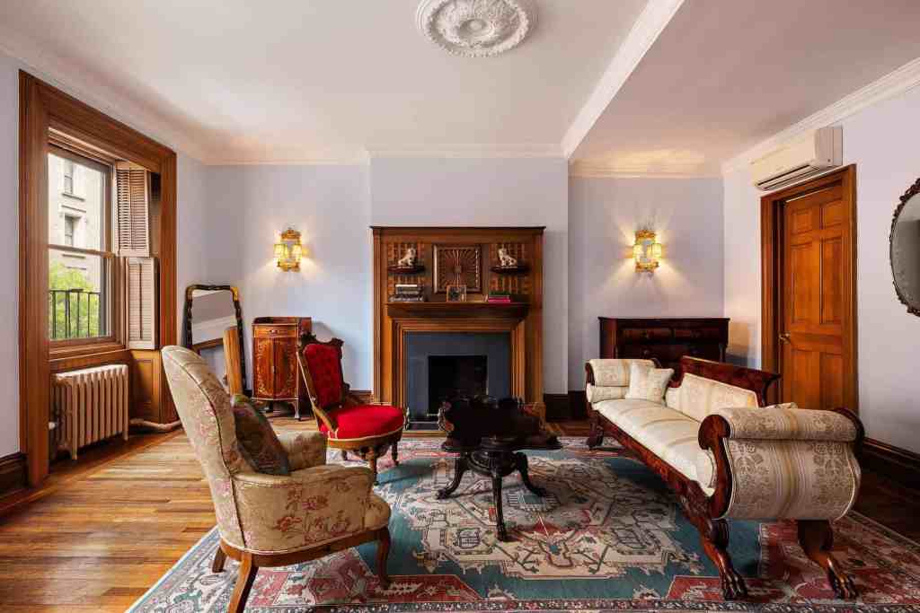 Vintage living room with antique furniture, fireplace, and hardwood floors.