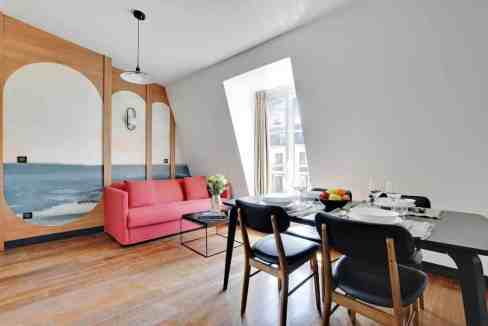 Modern living room with pink sofa and dining area in a serviced apartment.