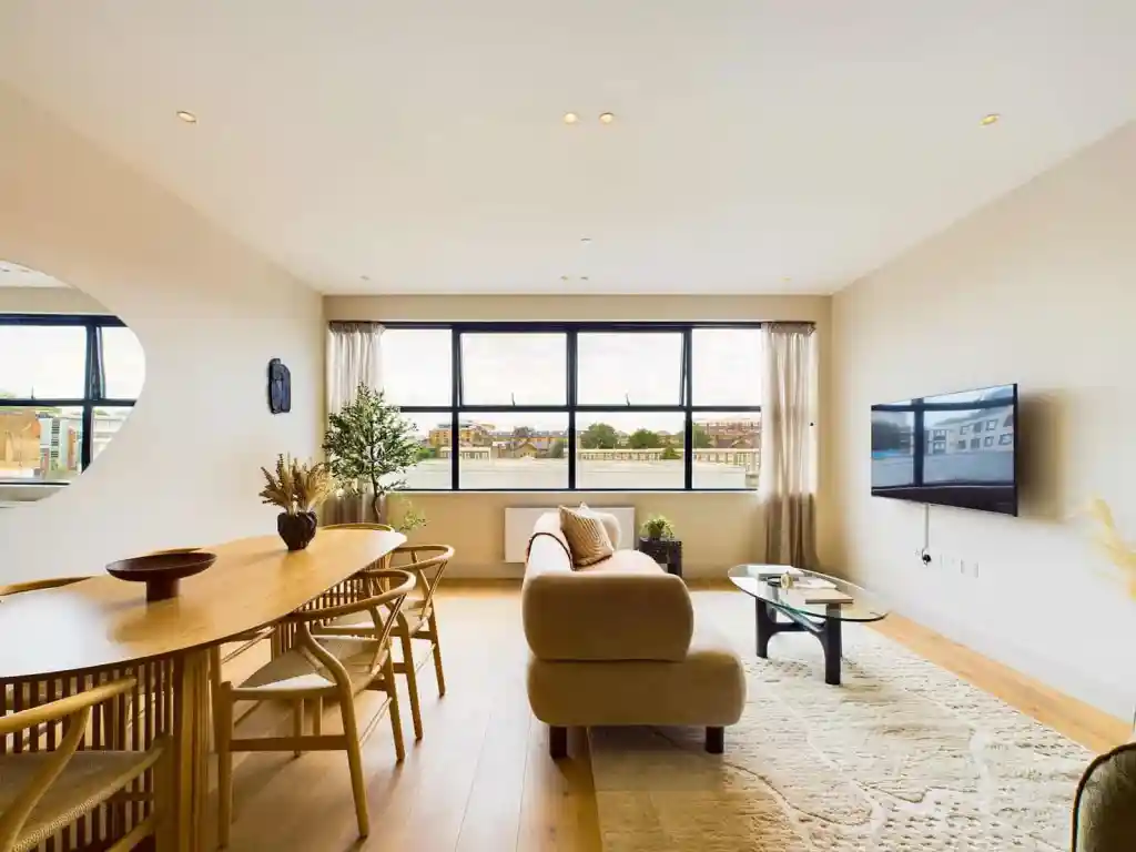Bright living room with large window, sofa, and wall-mounted TV.