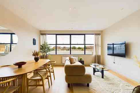 Bright living room with large window, sofa, and wall-mounted TV.