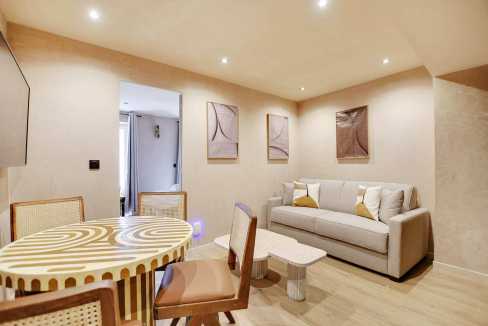 Modern living room with beige walls, white sofa, and abstract art decor.
