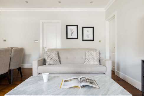 Bright living room with white walls, beige sofa, and framed artwork.