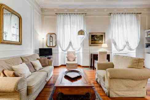 Cozy and elegant living room with vintage furniture, white curtains, and warm lighting.