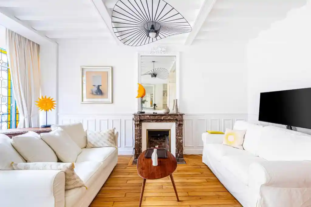 Bright modern living room with white sofas, fireplace, and stylish decor elements.