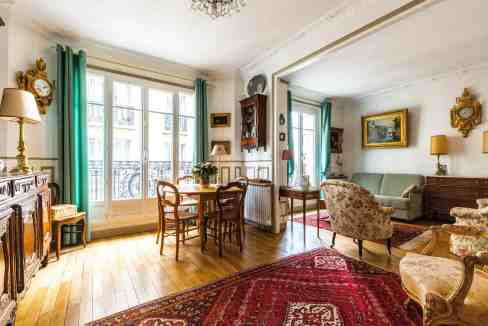 Bright living room with vintage furniture, large windows, and classic decor.