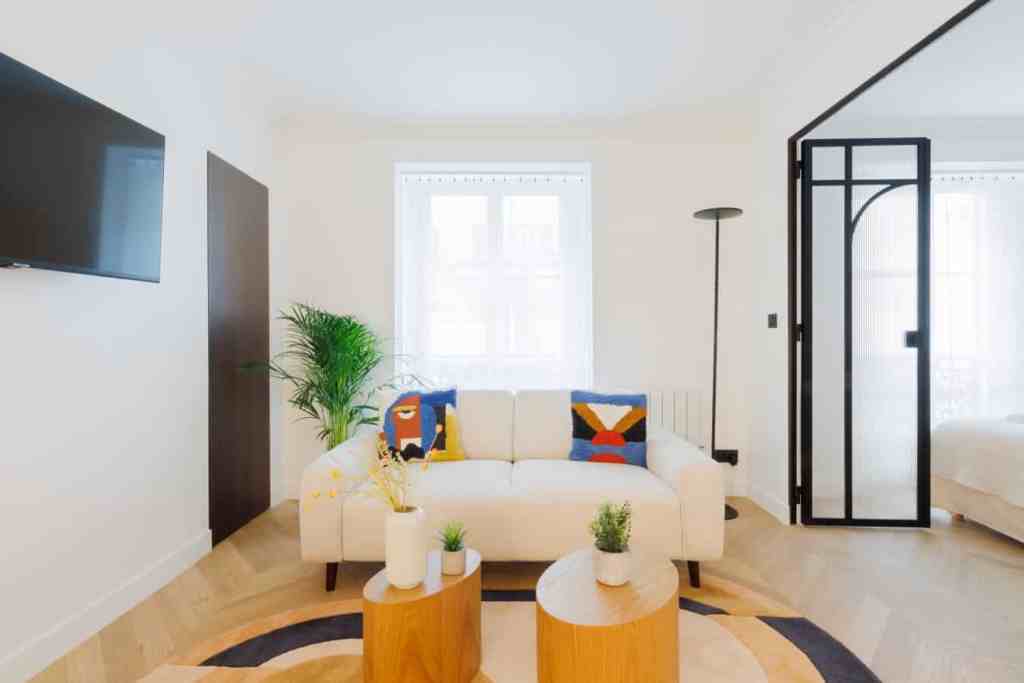 Modern living room with white sofa, colorful pillows, and natural light.
