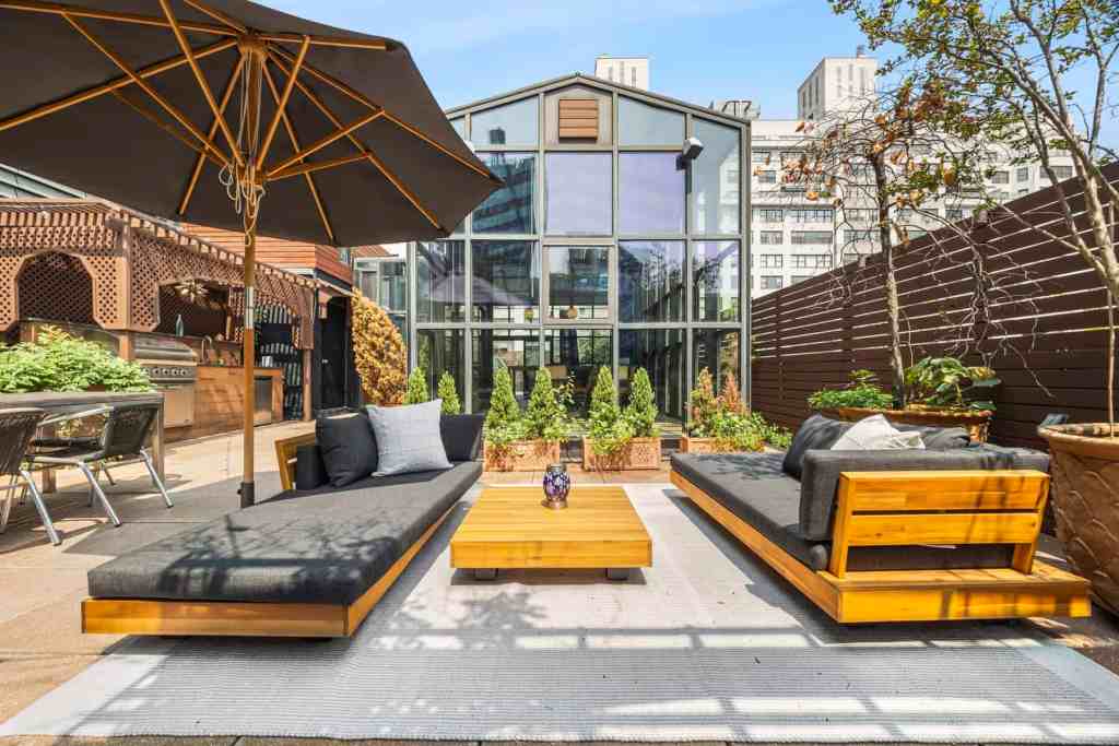 Outdoor rooftop lounge with modern furniture and cityscape backdrop.
