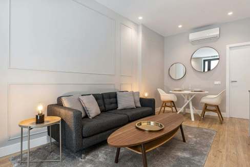 Elegant living room with a dark gray sofa, wooden coffee table, and stylish mirrors on the wall.