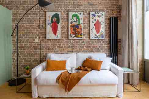 Modern living room with white sofa, colorful artwork, and natural light.