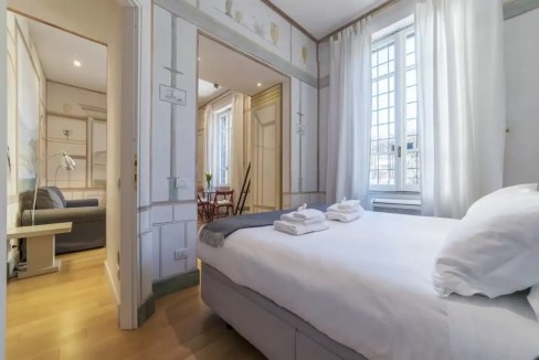 Bright bedroom featuring large windows, white curtains, and stylish interior design. Perfect for rel.