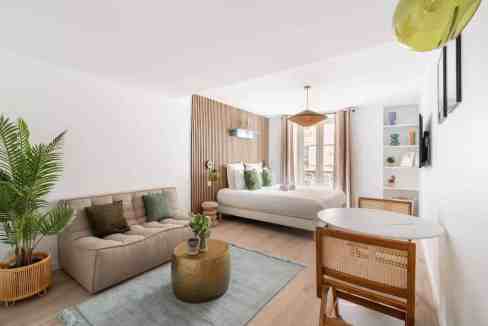 Modern living room with sofa, coffee table, and bedroom view in a serviced apartment.