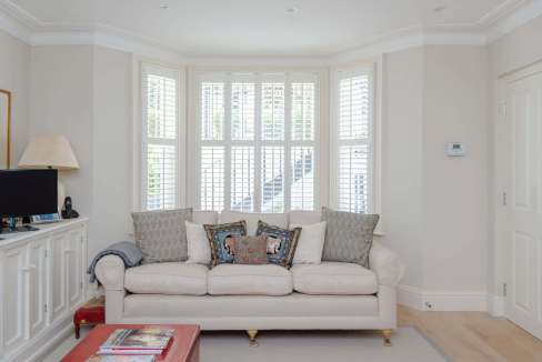 Bright living room with large bay windows and elegant decor.