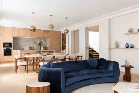 Spacious living room with navy velvet sofa and open-plan kitchen.