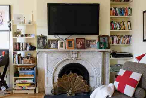 Comfortable living room featuring a fireplace, bookshelves, and cozy seating area with decorative cu.