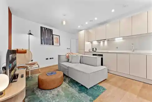 Contemporary living room with sofa, artwork, and kitchen in a serviced apartment.