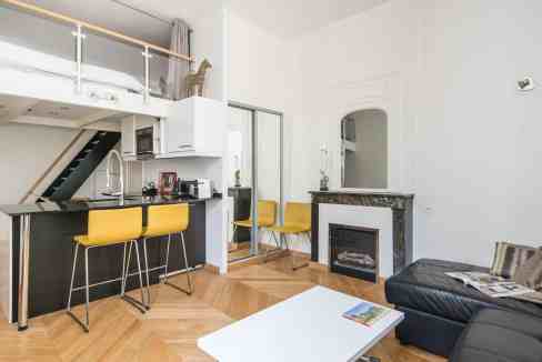 Modern serviced apartment living room with black sofa and yellow chairs.