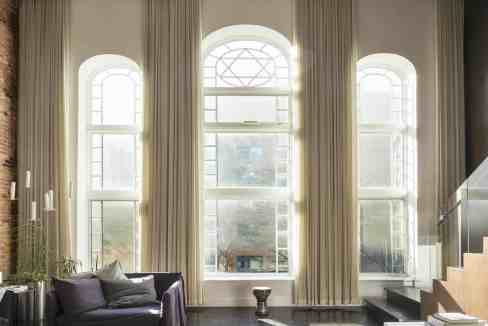 Bright living room featuring expansive arched windows and sheer curtains for natural light.