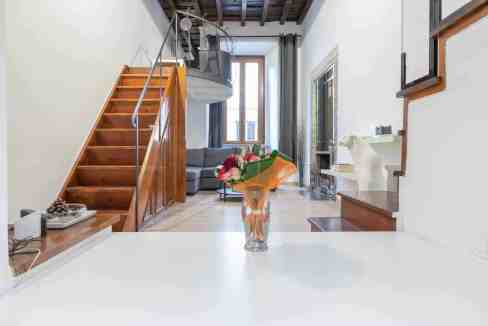 Modern living room with wooden staircase, large window, and contemporary decor.