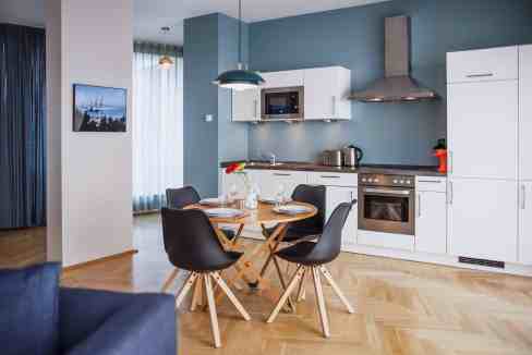 Modern kitchen with dining table and black chairs in a contemporary home setting.