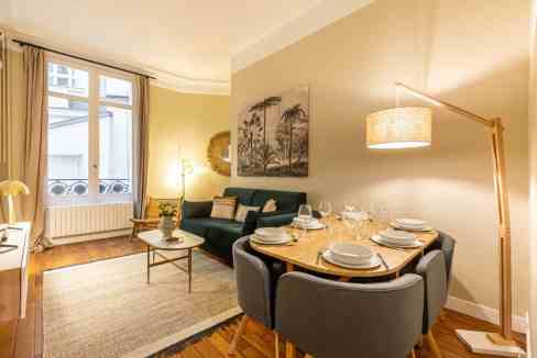 Cozy living and dining room with modern decor, large window, and warm lighting, perfect for relaxing.