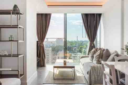 Bright living room with large window overlooking London skyline.