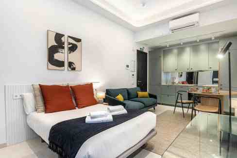 Contemporary living room with open kitchen, minimalist design, and cozy seating area.