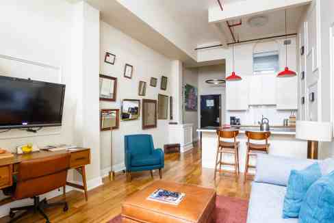 Cozy living room with modern furniture, wall art, and open kitchen in a stylish apartment.