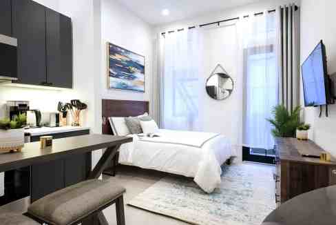 Bright, airy bedroom with large windows, white walls, and contemporary furnishings.