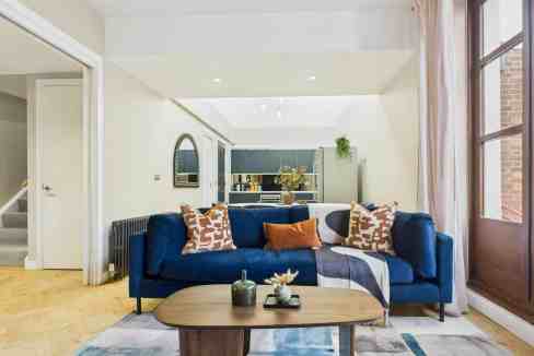 Bright living room with blue sofa, wooden coffee table, and large windows.
