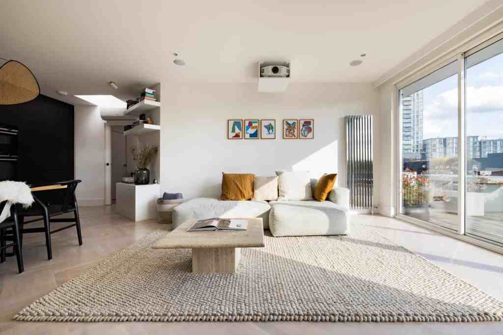 Bright living room with large windows and cityscape view, stylish furniture, and minimalist decor.