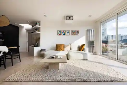 Bright living room with large windows and cityscape view, stylish furniture, and minimalist decor.