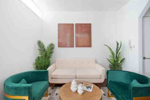 Contemporary living room with white sofa, green chairs, and minimalist decor.