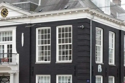 Historic black wooden building with large windows in Amsterdam Oosterpark.