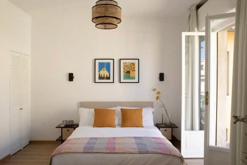 Bright bedroom with white walls, double bed, and open balcony door in Florence Arno Glow.