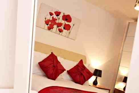 Cozy bedroom with red accents and modern decor in serviced apartment.