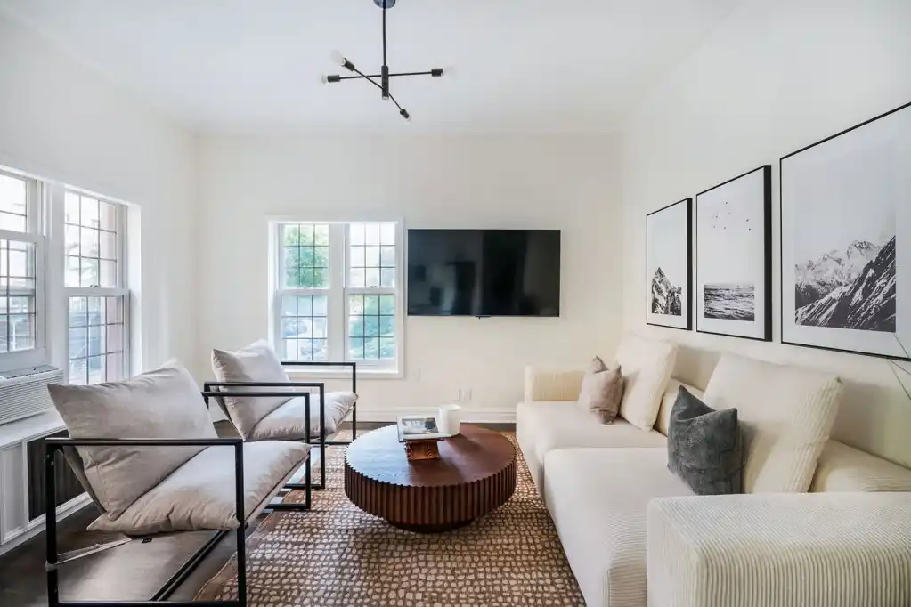 Bright living room with large windows, modern furniture, and wall art in Greenwich Village.
